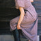side view of model wearing brown striped midi dress with puff sleeves, v-waistline and tie back