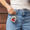 model holding tan needlepoint keychain kit with green trim and red and pink cherry print and gold hardware
