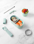 circular mint bamboo snack box with grey elastic closure on table with other styles