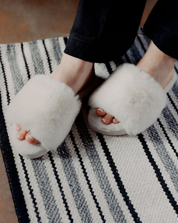 model wearing white faux fur slippers