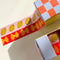 set of two rolls of washi tape: pink tape with olives, and red with bowtie pasta on the table