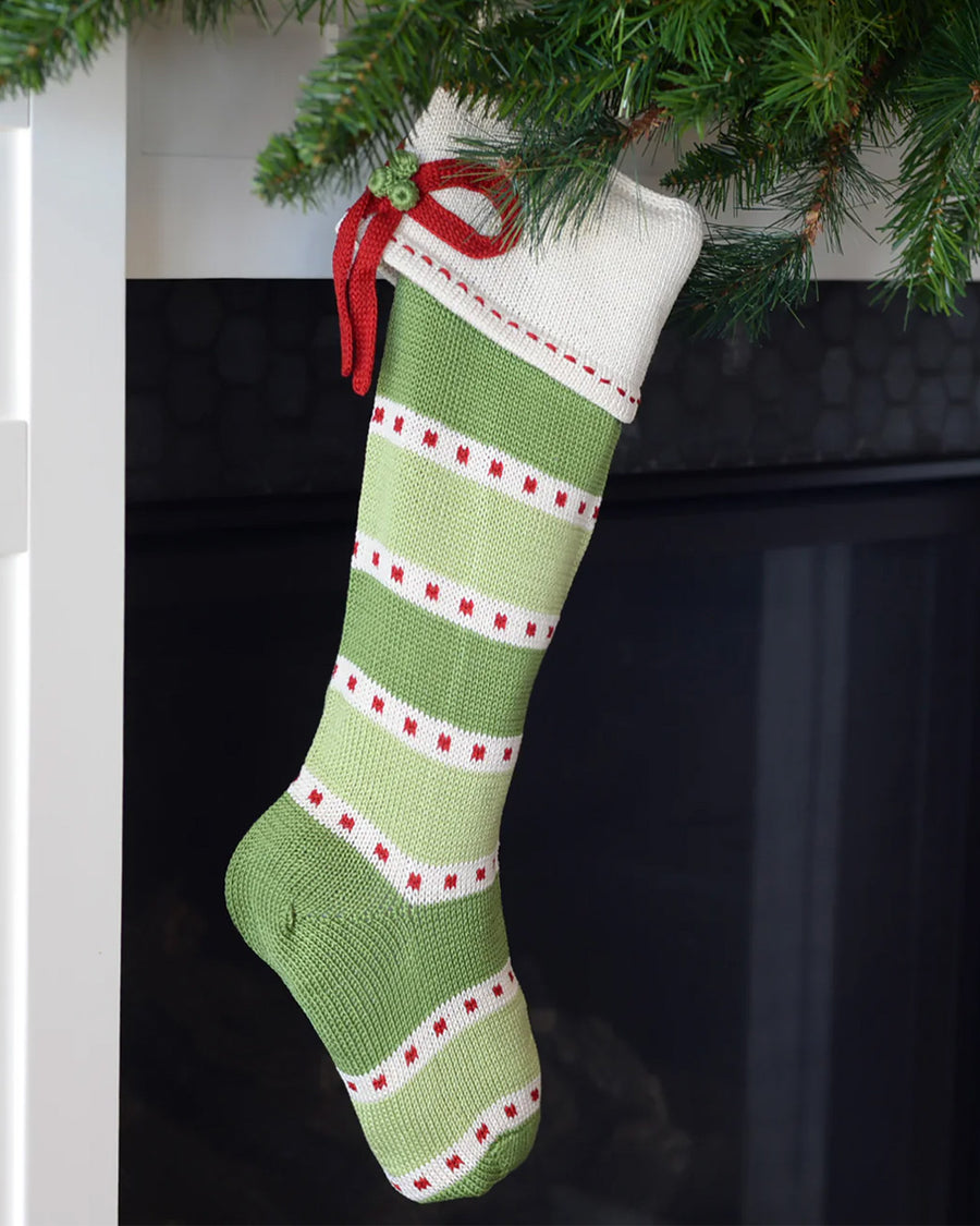 green and white stripe cotton stocking with cream cuff, red box and red dot detail hanging from a fireplace
