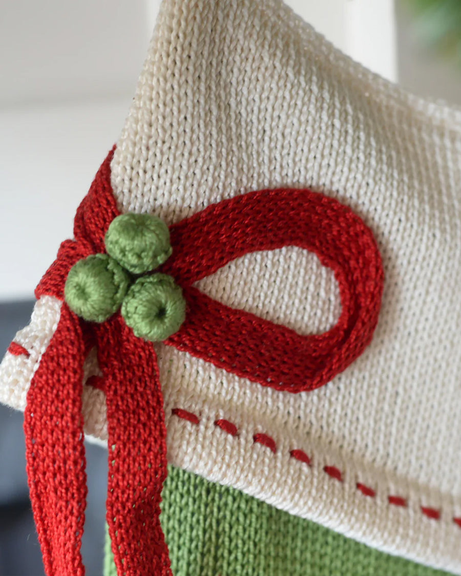 up close of bow detail on green and white stripe cotton stocking with cream cuff, red box and red dot detail
