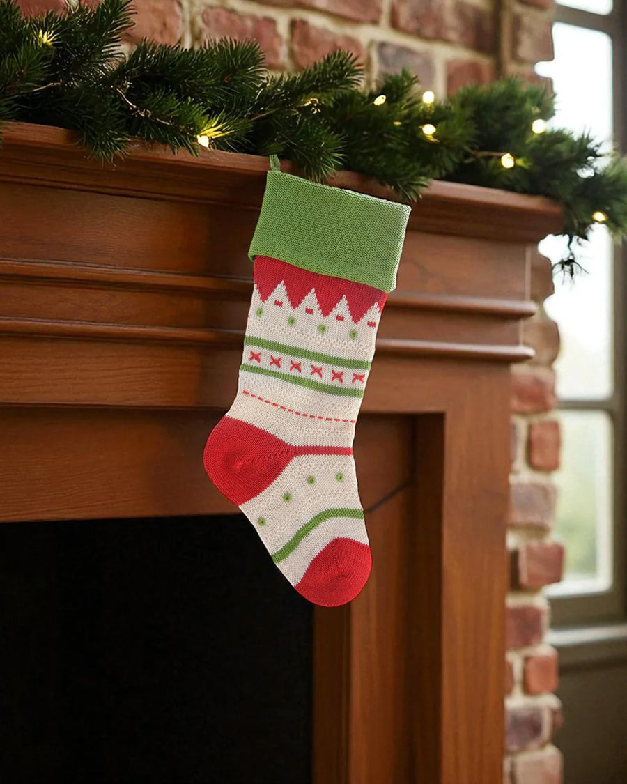 tan cotton stocking with green cuff, ed trim, and mixed print stripes in red and green hanging from a mantle