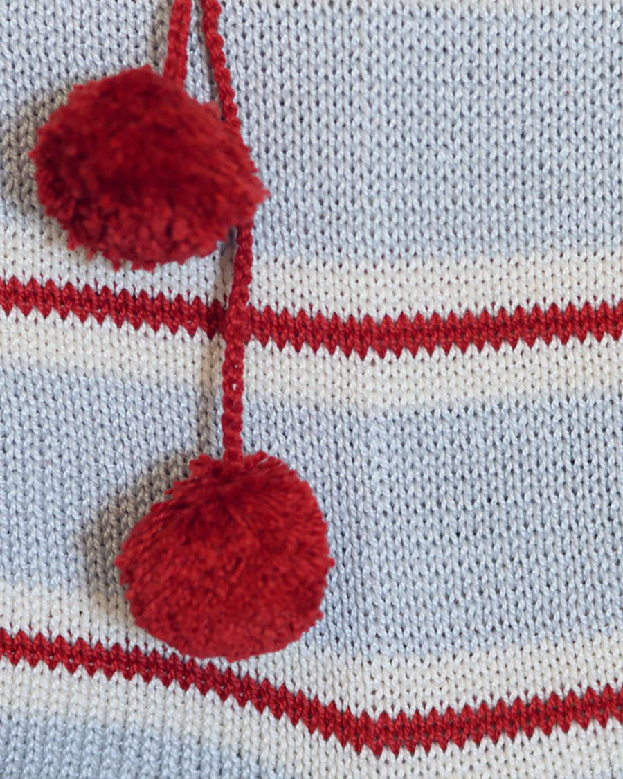 up close of grey cotton stocking with red and white thin stripes, red trim on the cuff and red pom pom detail