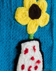 up close of blue towel with yarn flower and flower vase graphic near the bottom