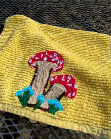 yellow towel with yarn red mushroom design near the bottom