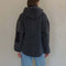 back view of model wearing charcoal sherpa sweater with quarter zip, hood, and elbow patches