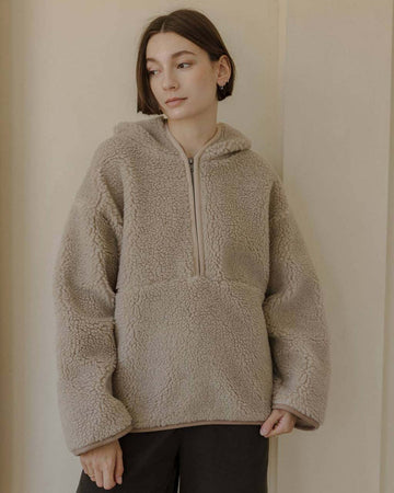 model wearing taupe sherpa sweater with quarter zip, hood, and elbow patches