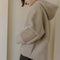 side view of model wearing taupe sherpa sweater with quarter zip, hood, and elbow patches
