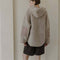 back view of model wearing taupe sherpa sweater with quarter zip, hood, and elbow patches