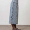side view of model wearing light denim midi skirt with brown side tie details