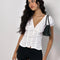 model wearing white cotton short sleeve blouse with deep v-neck, button front and corset waist and black shorts