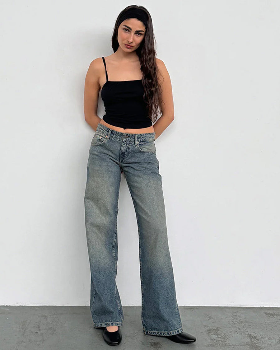 model wearing blueish-green low rise wide leg denim and black tank