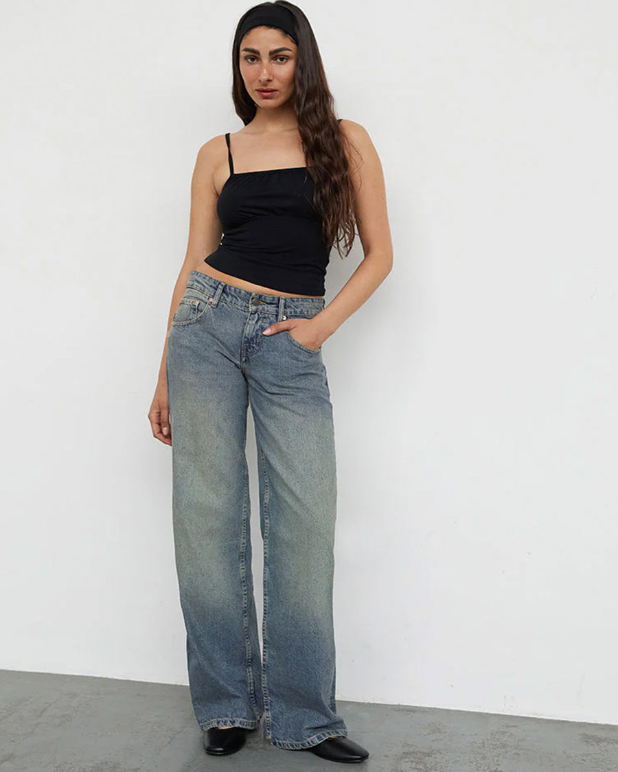 model wearing blueish-green low rise wide leg denim and black tank