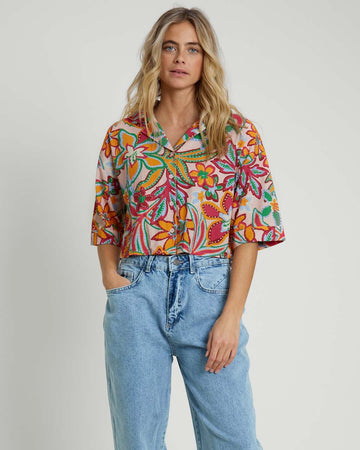 model wearing light pink seer sucker cropped button down top with colorful abstract floral print