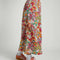 side view of model wearing light pink midiaxi skirt with elastic waist, side ties and colorful abstract floral print