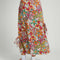 back view of model wearing light pink midiaxi skirt with elastic waist, side ties and colorful abstract floral print