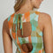 up close of model wearing blue, green, orange, and white midi dress with cut out back detail