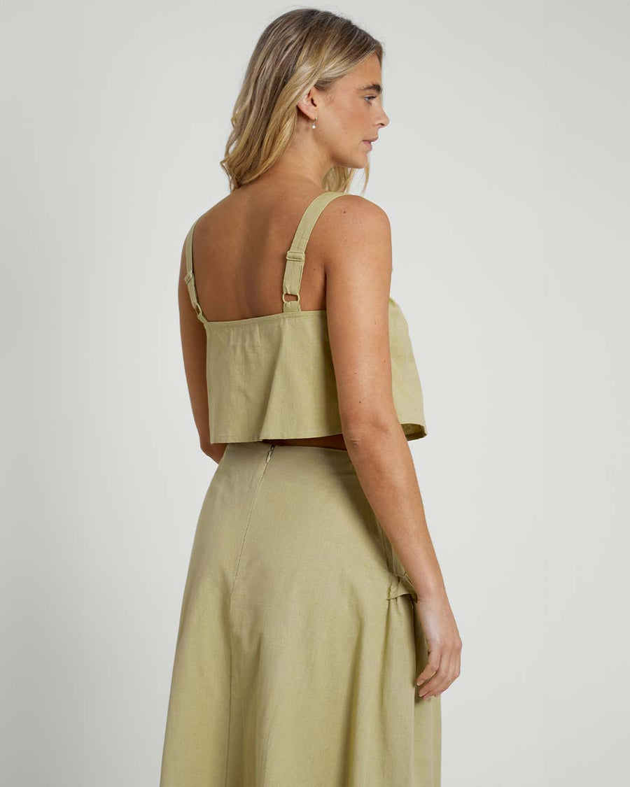 back view of model wearing moss cropped linen tank with ruffle bust detail and matching midi skirt