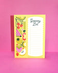 lined grocery list notepad with slightly glittery fruits and veggies on the side