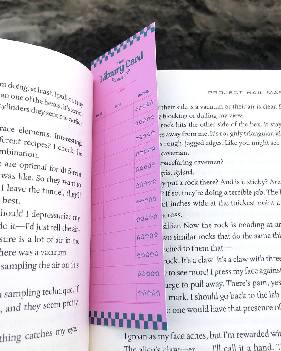 purple library card reading tracker bookmark in book