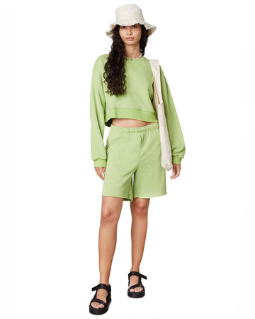 model wearing matcha mid length sweat shorts with raw hem and matching cropped top