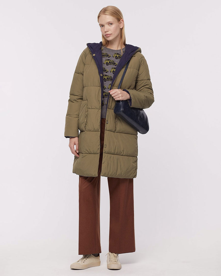 model wearing green knee length puffer coat with patch pockets and hood