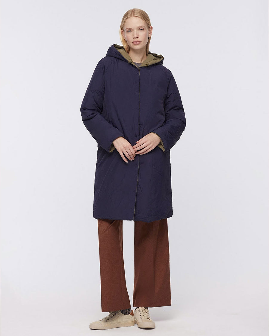 model wearing reversed dark blue knee length coat with hood