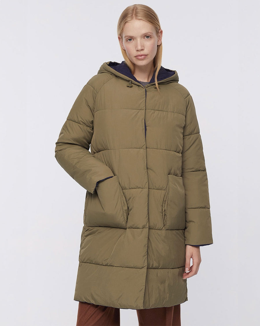 up close of model wearing green knee length puffer coat with patch pockets and hood