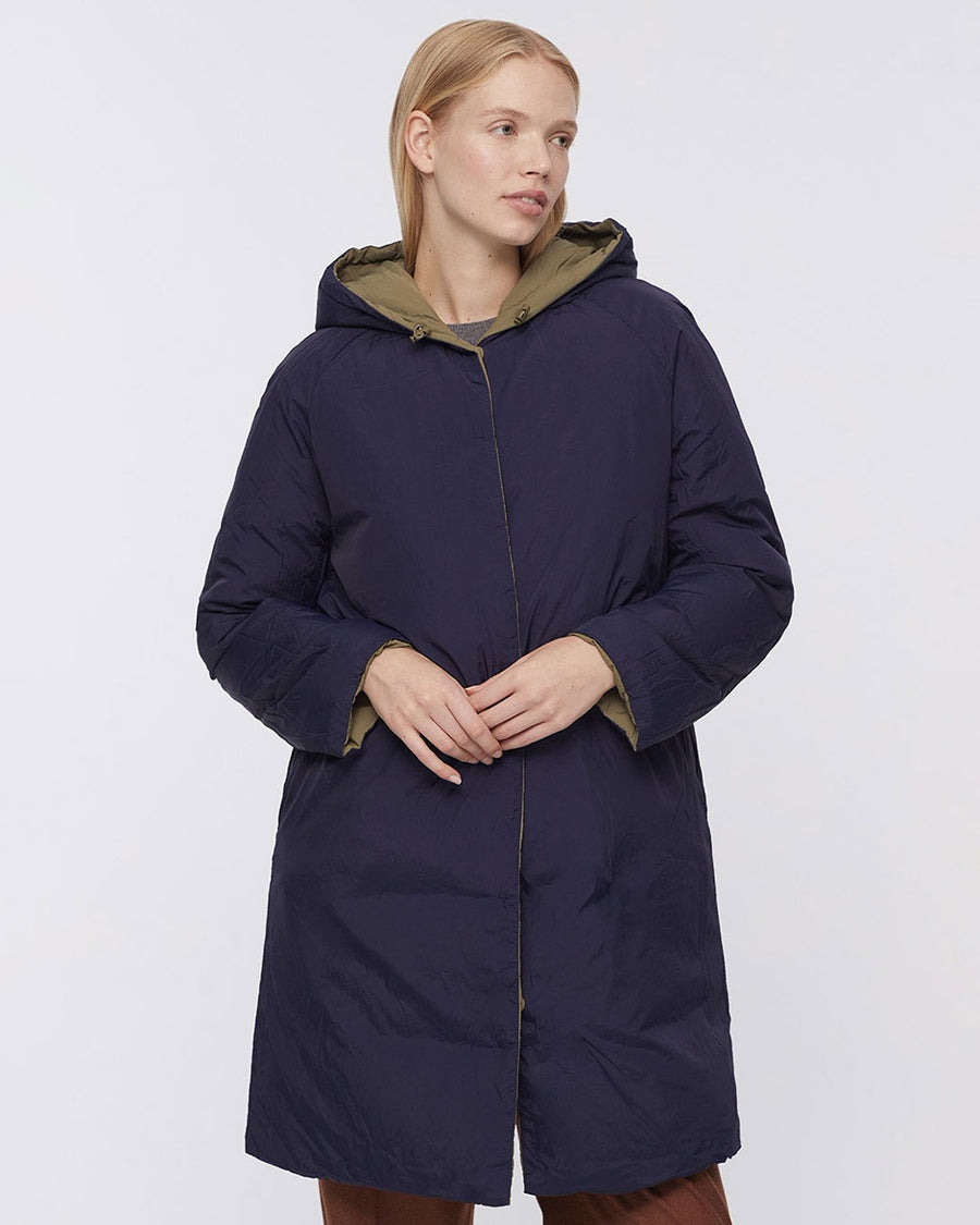up close of model wearing reversed dark blue knee length coat with hood