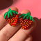 model holding small strawberry stud earrings
