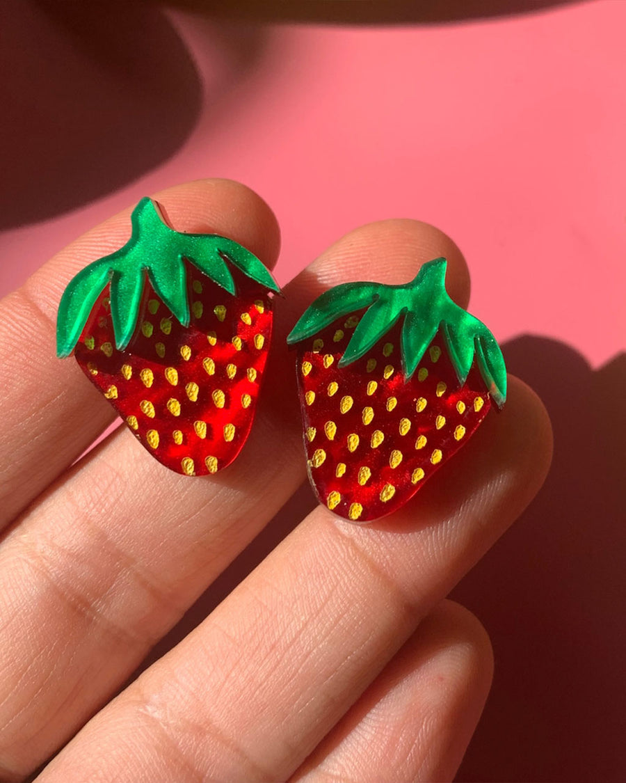 model holding small strawberry stud earrings