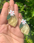 model holding lemon shaped dangle earrings with flower on top