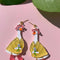 goose wearing yellow coat, pink boots and hat dangle earrings