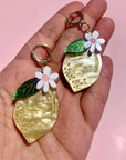 model holding lemon shaped dangle earrings with flower on top