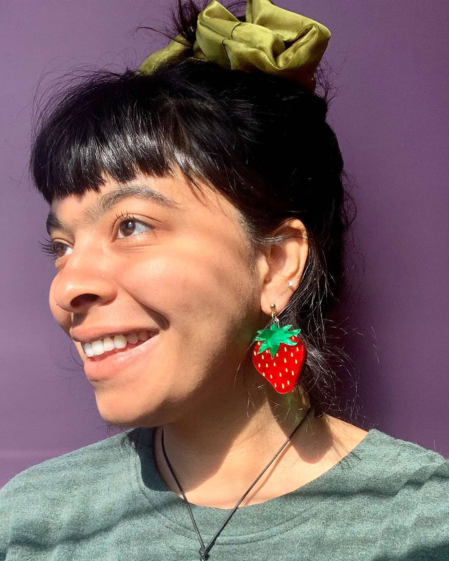model wearing large strawberry shaped dangle earrings
