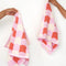 model holding set of 2 hand towels with coral, pink and white checked pattern