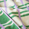 up close of cream hand towels with kelly green and lilac stripes (and the reversible side is green with cream and lilac stripes)
