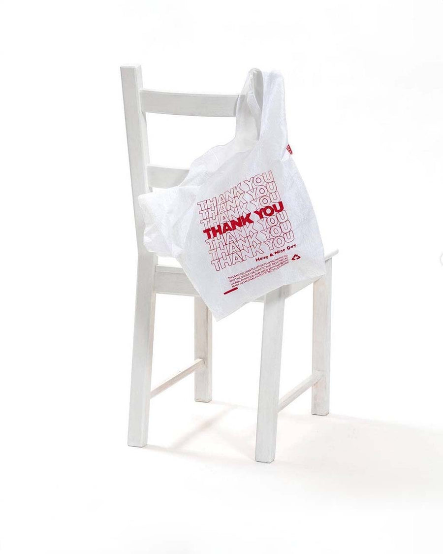 embroidered red thank you reusable bag hanging on back of a chair
