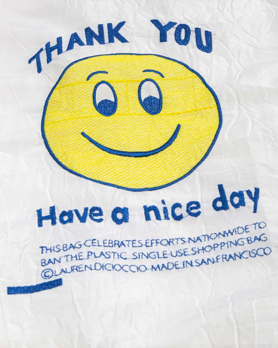 up close of white reusable bag with smiley thank you embroidery