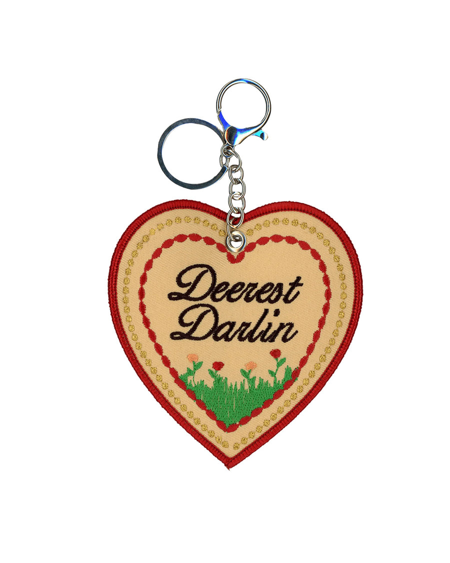 reverse side of keychain with black 'deerest darlin' with a flower field beneath it.