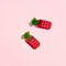 set of two strawberry candy shaped hair clips on a pink background