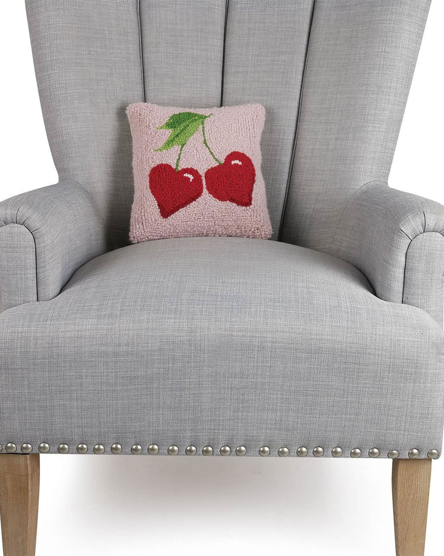 pink throw pillow with heart cherries design on chair