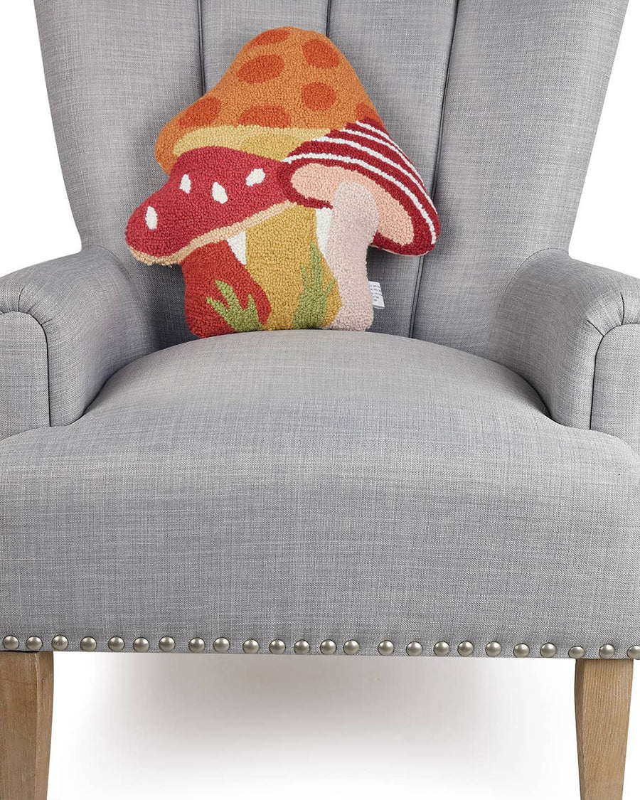 mushroom trio throw pillow with orange polka dot, red and white stripe and red and white mushrooms on chair