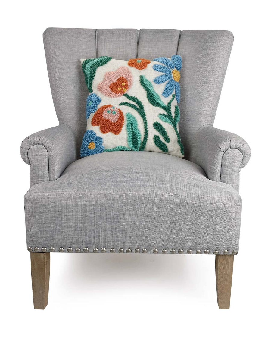white square throw pillow with colorful flower print on grey chair