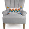 white throw pillow with wavy rainbow print and blue and yellow tassels on a grey chair