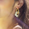 up close of model wearing thick gold hoop earrings with acrylic white flower charm