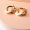 front view of thick gold hoop earrings with acrylic white flower charm