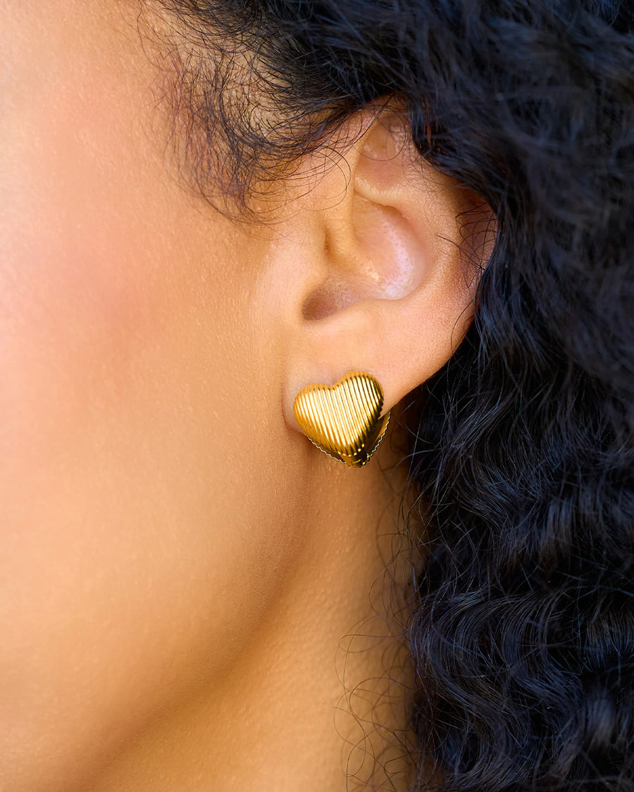 model wearing gold textured heart huggies